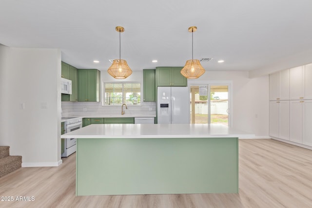 kitchen featuring a center island, white appliances, backsplash, light wood-type flooring, and decorative light fixtures