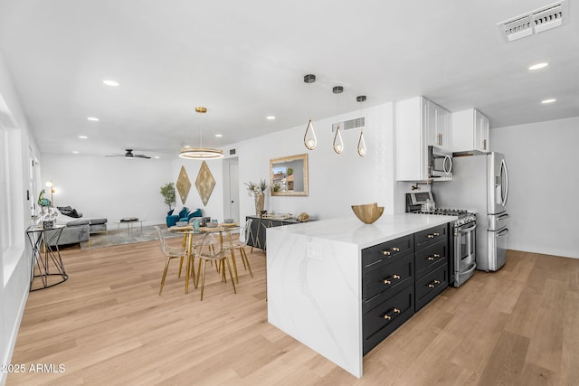 14635 N 37th Pl, Phoenix, AZ 85032 - kitchen featuring appliances with stainless steel finishes, white cabinetry, dark cabinets, light wood-style flooring, and light stone counters