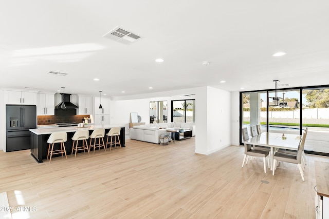 interior space featuring tasteful backsplash, visible vents, high quality fridge, light countertops, and wall chimney range hood