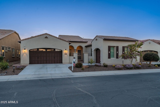 mediterranean / spanish home with an attached garage, driveway, a gate, and stucco siding