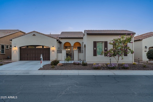 view of front of home featuring an attached garage, concrete driveway, a tiled roof, a gate, and stucco siding