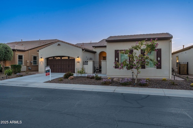 view of front facade featuring an attached garage, fence, concrete driveway, and stucco siding