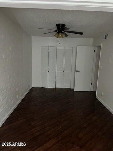 unfurnished bedroom featuring ceiling fan, dark hardwood / wood-style flooring, and a closet