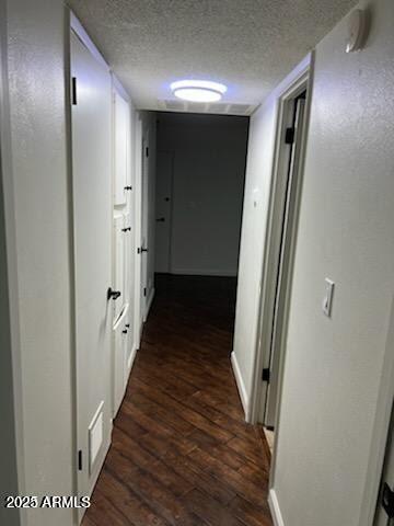 corridor featuring a textured ceiling and dark hardwood / wood-style flooring