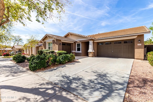 view of front of home featuring a garage, a tile roof, driveway, stone siding, and stucco siding