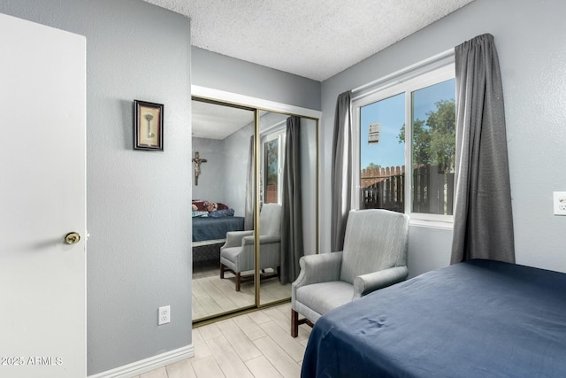 8623 W Indianola Ave, Phoenix, AZ 85037 - bedroom featuring a closet, a textured wall, baseboards, light wood-type flooring, and a textured ceiling