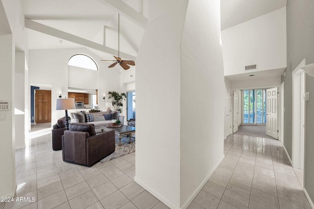 tiled living room with ceiling fan, beam ceiling, and high vaulted ceiling