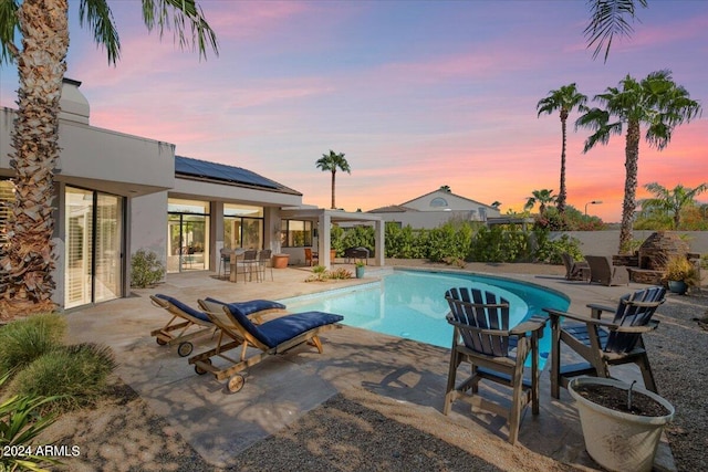 pool at dusk with a patio area