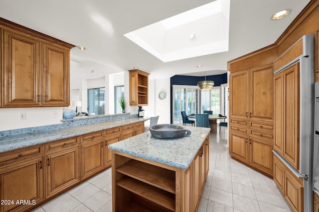 kitchen with pendant lighting, light stone counters, a center island, light tile patterned flooring, and a notable chandelier