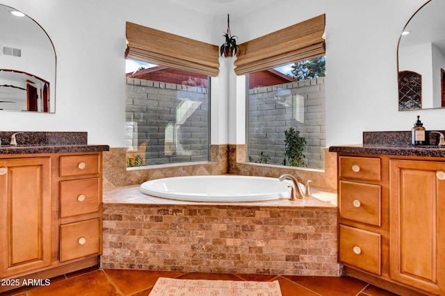 bathroom featuring tile patterned flooring, vanity, and a relaxing tiled tub