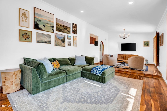 living room with an inviting chandelier, lofted ceiling, ornamental molding, and wood-type flooring