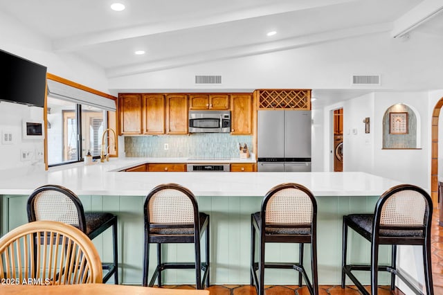 kitchen featuring appliances with stainless steel finishes, vaulted ceiling with beams, sink, and backsplash