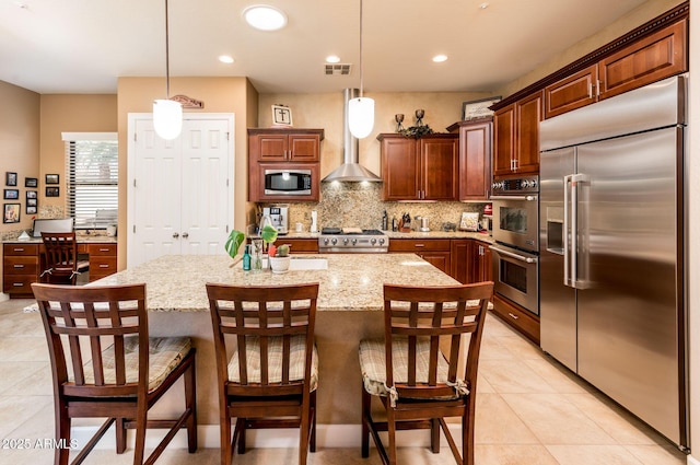 kitchen featuring built in appliances, pendant lighting, and a center island