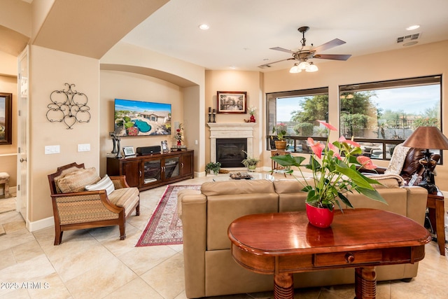 living room featuring light tile patterned floors, baseboards, visible vents, a fireplace with raised hearth, and recessed lighting