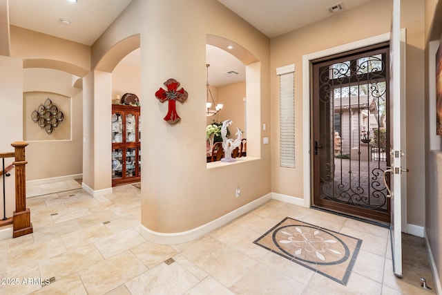 entrance foyer featuring baseboards, visible vents, and a chandelier