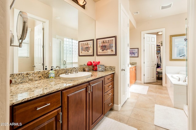 full bathroom featuring a walk in closet, a garden tub, visible vents, vanity, and tile patterned flooring