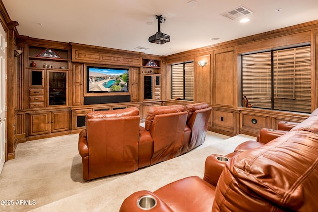 cinema room with built in features, visible vents, and light colored carpet