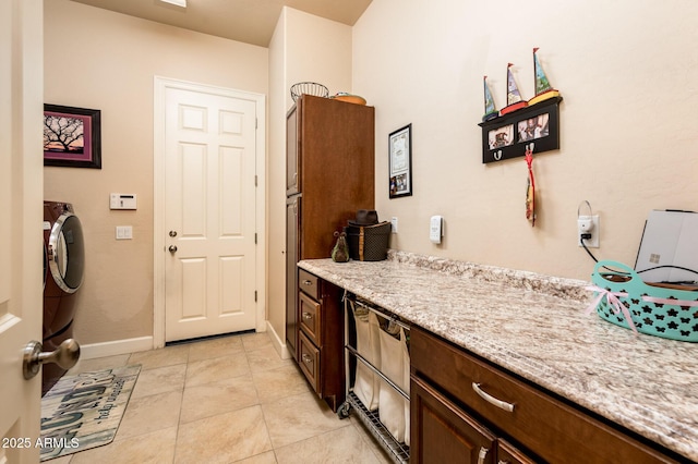 kitchen featuring light stone counters, dark brown cabinets, baseboards, and light tile patterned floors