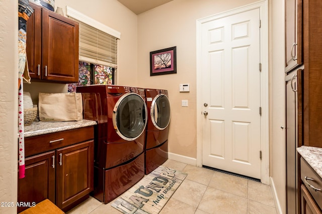 washroom featuring cabinets, washing machine and dryer, and light tile patterned floors