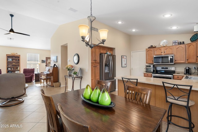 dining area with lofted ceiling, light tile patterned floors, ceiling fan with notable chandelier, and sink