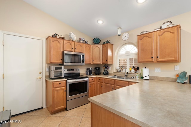 kitchen featuring vaulted ceiling, appliances with stainless steel finishes, sink, light tile patterned floors, and kitchen peninsula