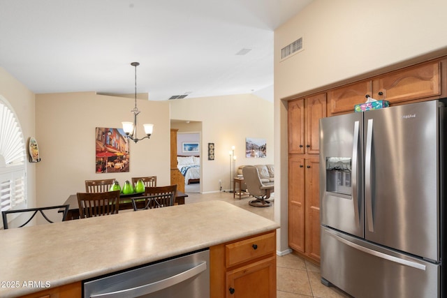 kitchen featuring lofted ceiling, a chandelier, light tile patterned floors, pendant lighting, and stainless steel appliances