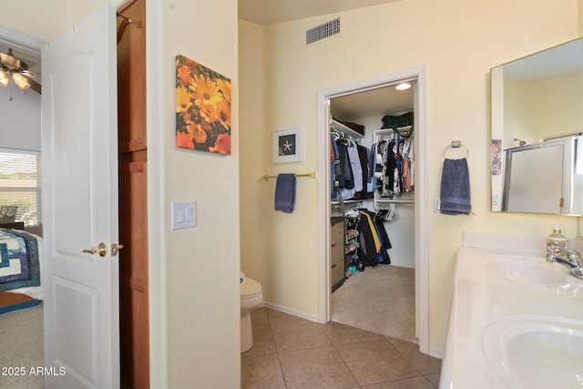 bathroom with tile patterned floors, toilet, vanity, a shower with door, and ceiling fan