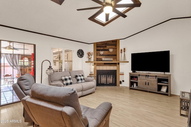 living room featuring hardwood / wood-style floors, ornamental molding, a tile fireplace, and ceiling fan