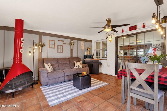 tiled living room with a wood stove and ceiling fan