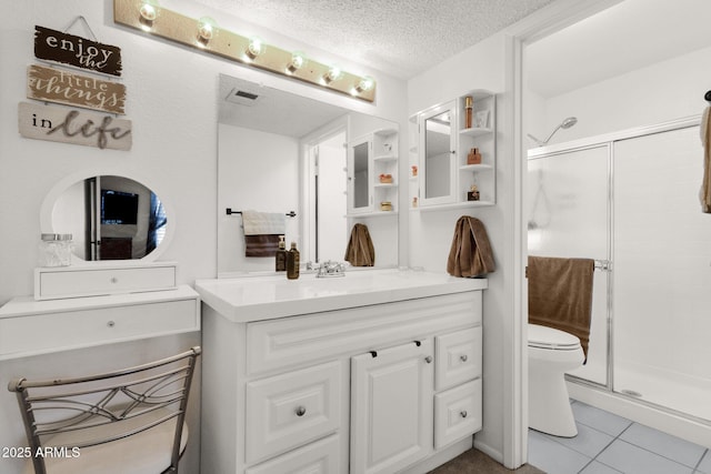 bathroom with vanity, a shower with door, toilet, and a textured ceiling