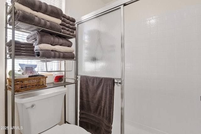 bathroom with a shower with door and toilet