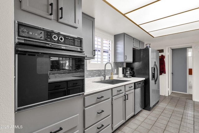 kitchen with light tile patterned flooring, tasteful backsplash, dishwasher, sink, and gray cabinetry