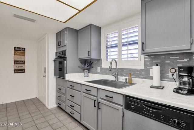 kitchen with dishwashing machine, sink, black oven, gray cabinetry, and tasteful backsplash