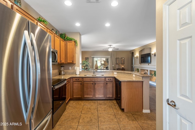 kitchen with kitchen peninsula, appliances with stainless steel finishes, light stone countertops, ceiling fan, and sink