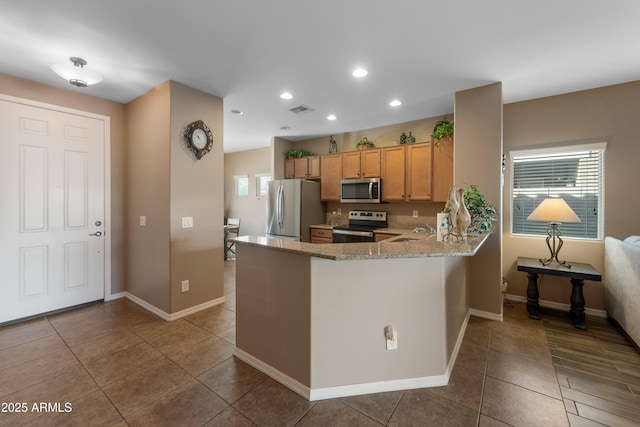 kitchen featuring kitchen peninsula, a wealth of natural light, sink, and stainless steel appliances