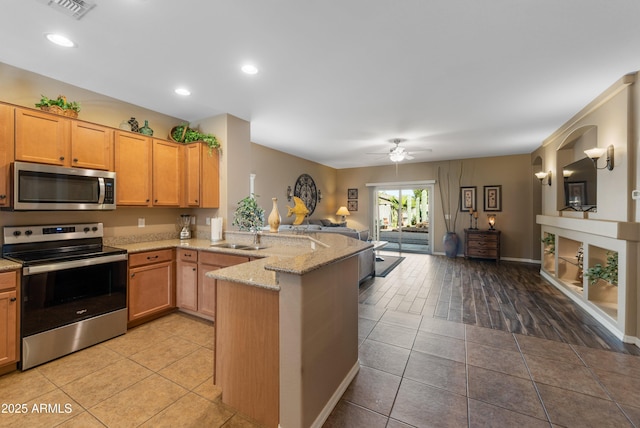 kitchen featuring sink, stainless steel appliances, light stone counters, kitchen peninsula, and light tile patterned flooring