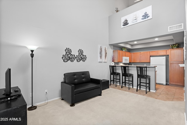 living room with a towering ceiling, light colored carpet, baseboards, and recessed lighting