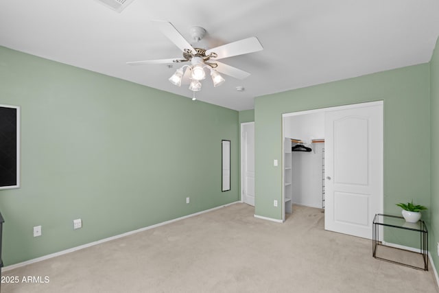unfurnished bedroom with carpet flooring, baseboards, a closet, a ceiling fan, and a spacious closet