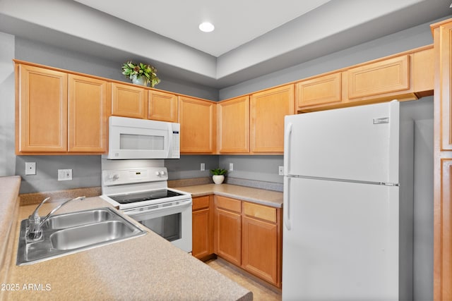 kitchen featuring white appliances, a sink, light countertops, and recessed lighting