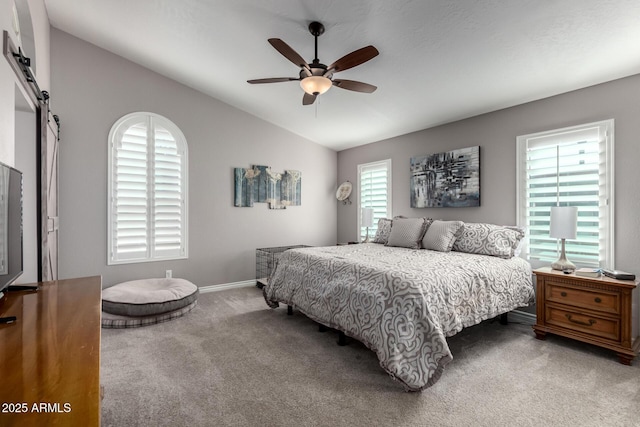 bedroom featuring lofted ceiling, ceiling fan, a barn door, and carpet