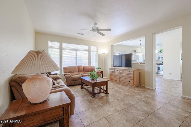 tiled living room featuring a textured ceiling and ceiling fan with notable chandelier