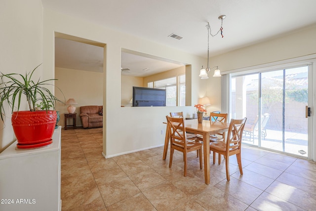 dining room with a healthy amount of sunlight, light tile patterned flooring, and an inviting chandelier