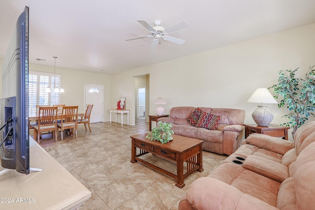 tiled living room featuring ceiling fan with notable chandelier