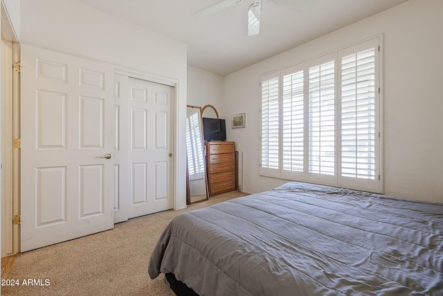 bedroom with ceiling fan, a closet, and light carpet