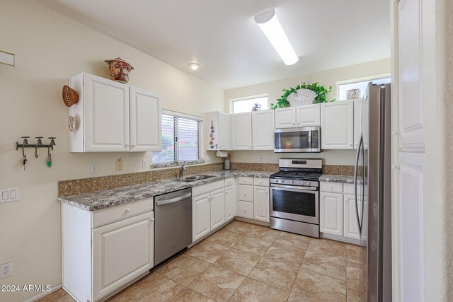 kitchen featuring white cabinetry, sink, light stone countertops, and appliances with stainless steel finishes