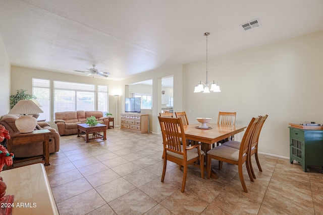 tiled dining room with a textured ceiling and ceiling fan with notable chandelier