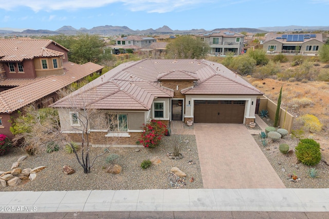 view of front of property featuring a garage, a tile roof, decorative driveway, a mountain view, and stucco siding