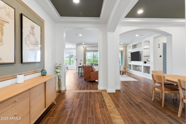 interior space featuring wood tiled floor, arched walkways, a raised ceiling, and recessed lighting