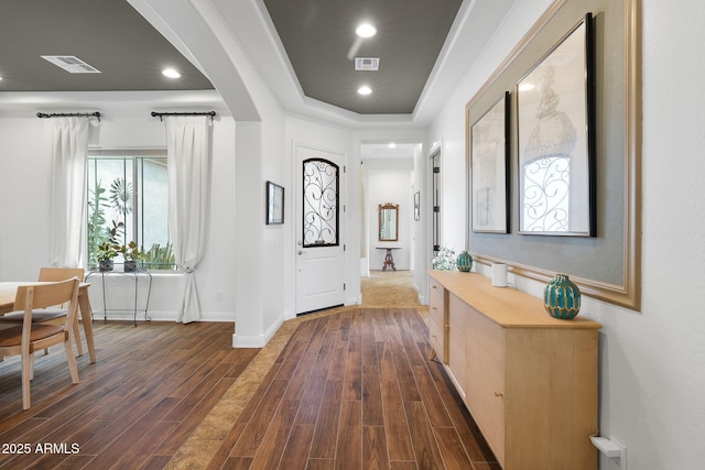 corridor featuring dark wood-style floors, arched walkways, and visible vents