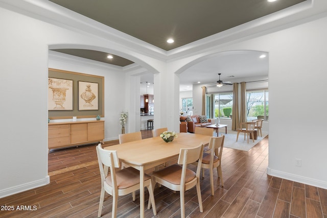 dining room with arched walkways, recessed lighting, baseboards, and wood tiled floor